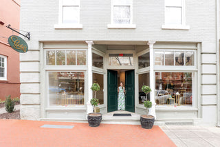 The outside of Cate's Boutique in downtown Anderson. Owner Caleigh Thomas holds the green double-doors open.